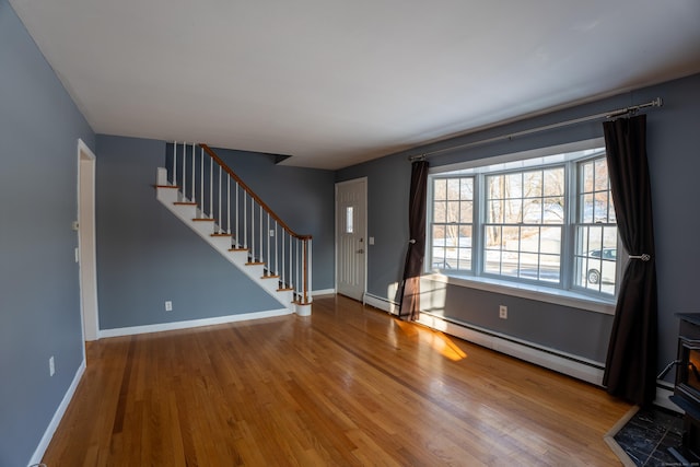 foyer entrance featuring hardwood / wood-style flooring, a baseboard radiator, and a wood stove