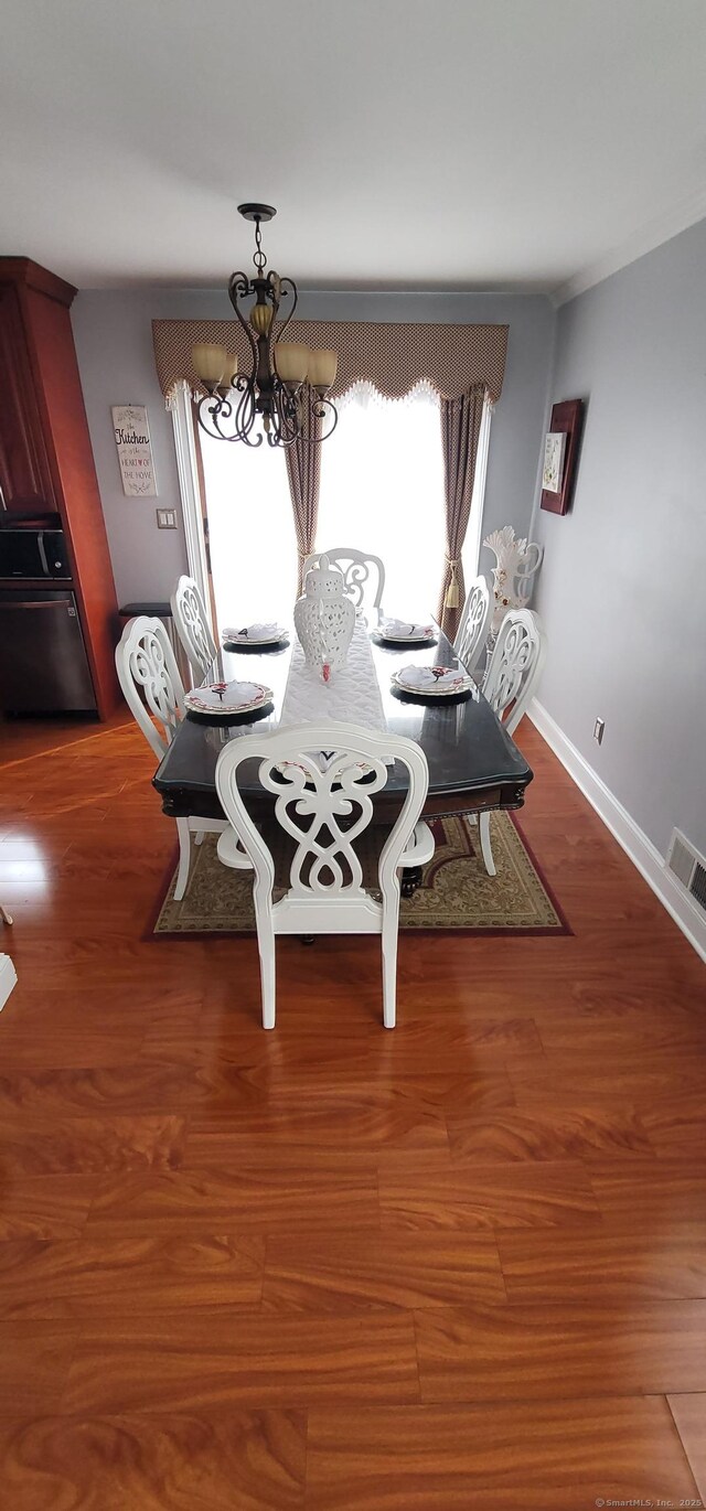 unfurnished dining area with dark wood-type flooring, plenty of natural light, and a chandelier