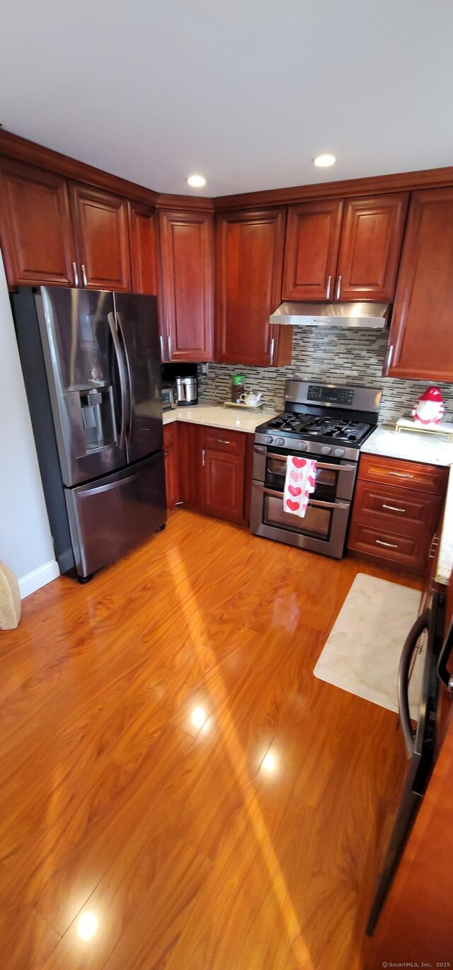 kitchen with stainless steel appliances, light wood-type flooring, and decorative backsplash