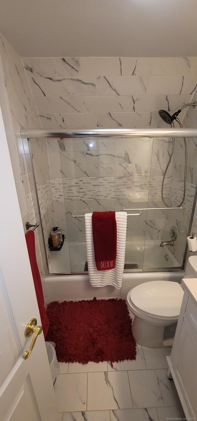 full bathroom featuring toilet, vanity, and shower / bath combination with glass door