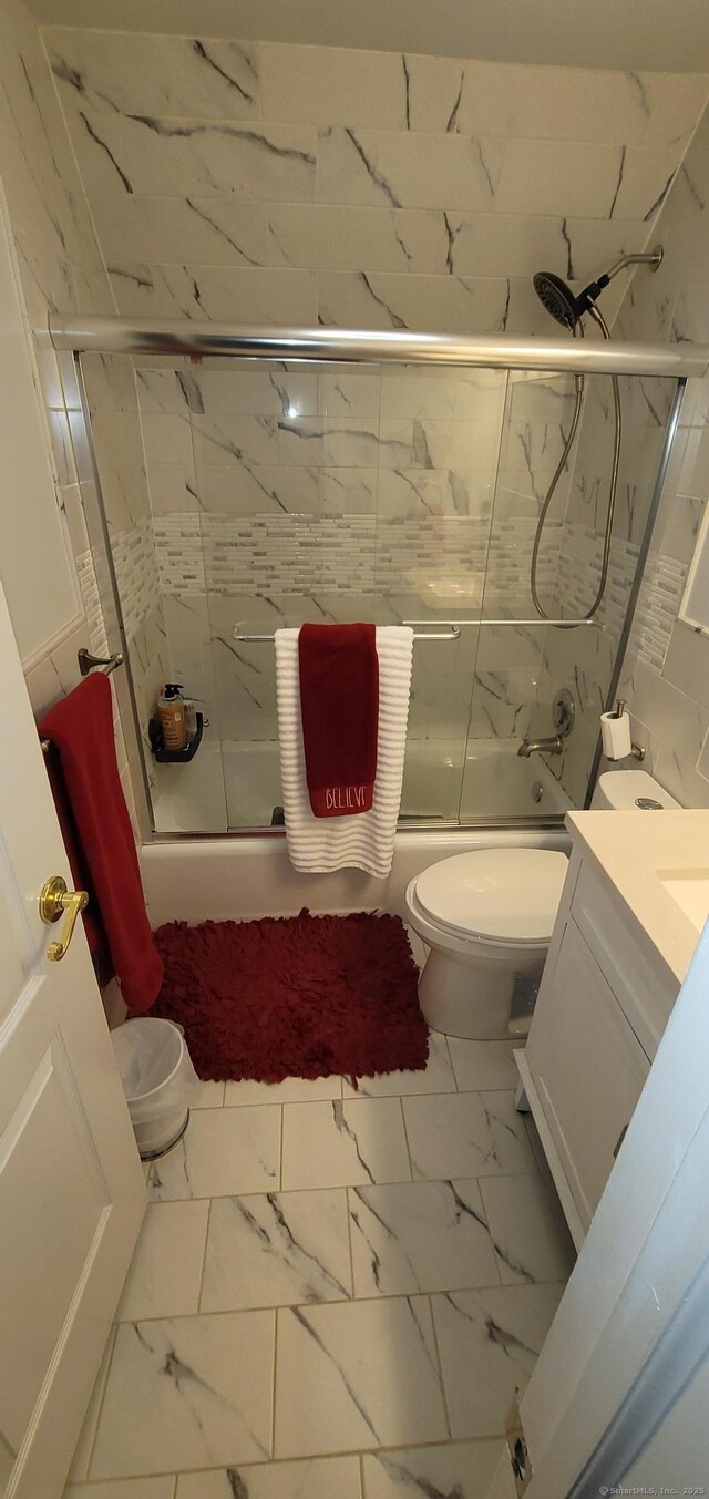 full bathroom with toilet, vanity, and bath / shower combo with glass door