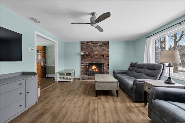 living room featuring ceiling fan, hardwood / wood-style floors, a fireplace, and baseboard heating