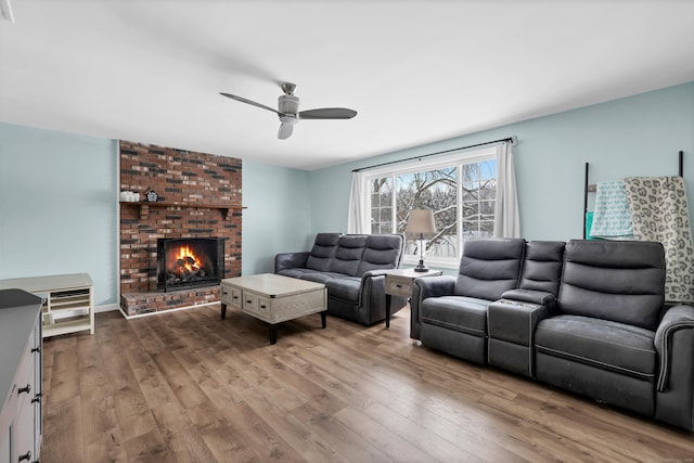 living room with ceiling fan, hardwood / wood-style floors, and a brick fireplace