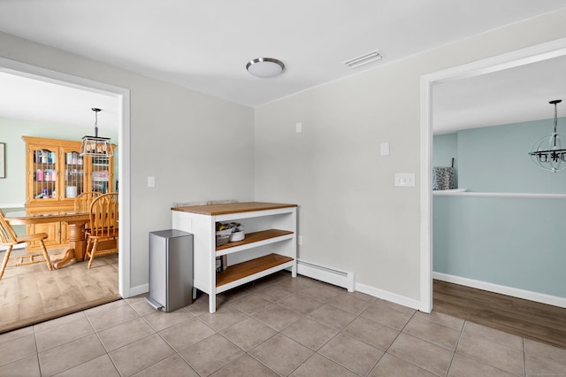 corridor with a baseboard radiator, light tile patterned floors, and a chandelier