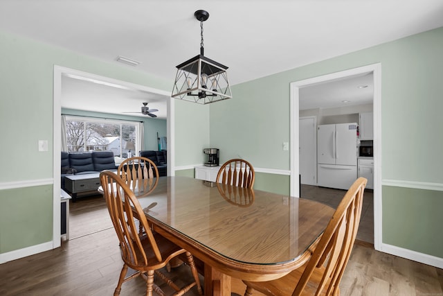 dining room featuring ceiling fan with notable chandelier and hardwood / wood-style floors