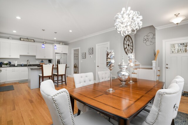 dining area with ornamental molding, light hardwood / wood-style floors, and a chandelier