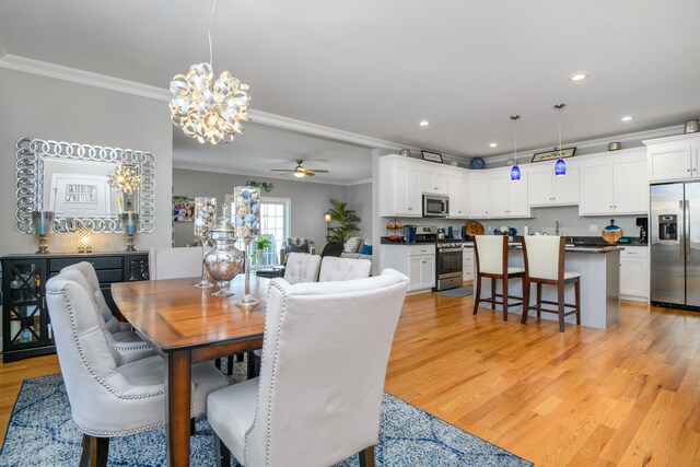 dining area with crown molding, sink, ceiling fan with notable chandelier, and light hardwood / wood-style floors