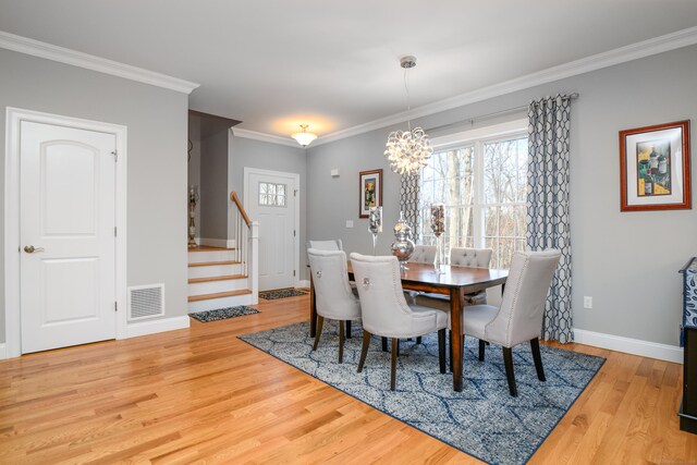 dining room featuring ornamental molding, an inviting chandelier, and light hardwood / wood-style flooring