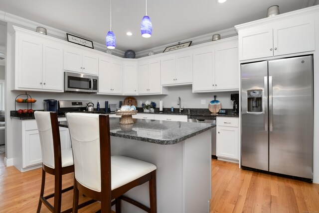 kitchen with light hardwood / wood-style flooring, a breakfast bar area, white cabinetry, stainless steel appliances, and decorative light fixtures