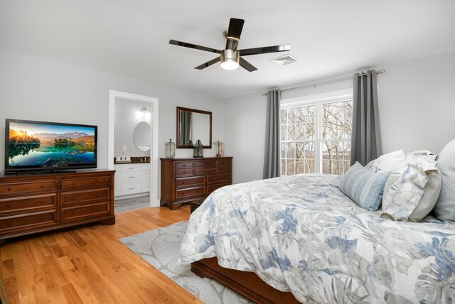 bedroom featuring ceiling fan, ensuite bath, and light wood-type flooring