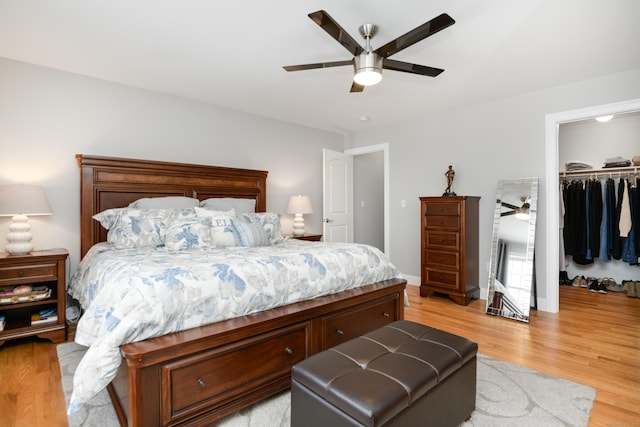 bedroom with ceiling fan, a walk in closet, a closet, and light wood-type flooring