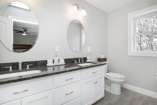 bathroom featuring hardwood / wood-style flooring, ceiling fan, vanity, and toilet