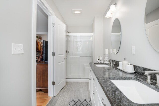 bathroom with walk in shower, vanity, and hardwood / wood-style flooring