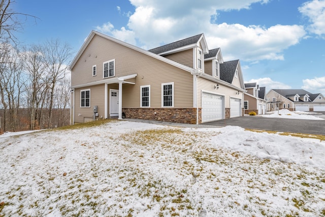 view of front of home featuring a garage, stone siding, and driveway