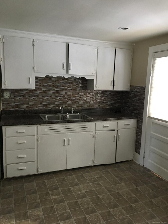 kitchen featuring sink, backsplash, and white cabinets