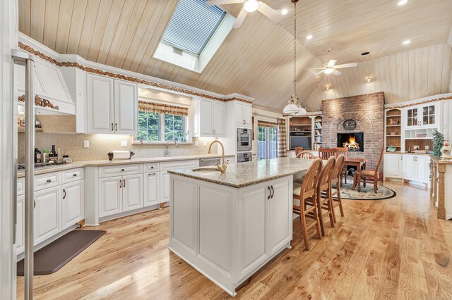 24 Brierwood Dr, Orange, CT 06477 - kitchen with ceiling fan, wooden ceiling, vaulted ceiling, a fireplace, and a kitchen island with sink