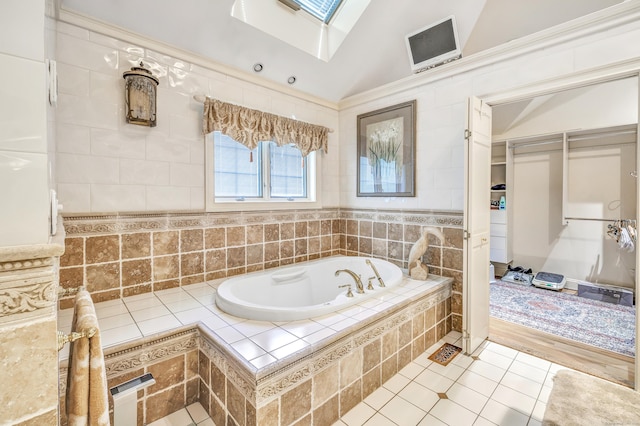 bathroom featuring tile patterned flooring, vaulted ceiling with skylight, and a relaxing tiled tub