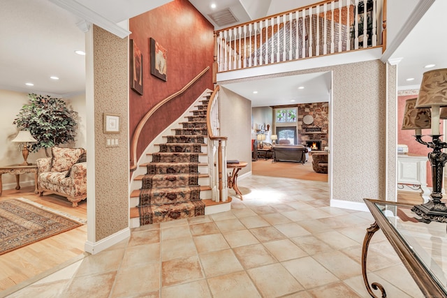 24 Brierwood Dr, Orange, CT 06477 - staircase featuring wallpapered walls, ornamental molding, a stone fireplace, recessed lighting, and tile patterned floors
