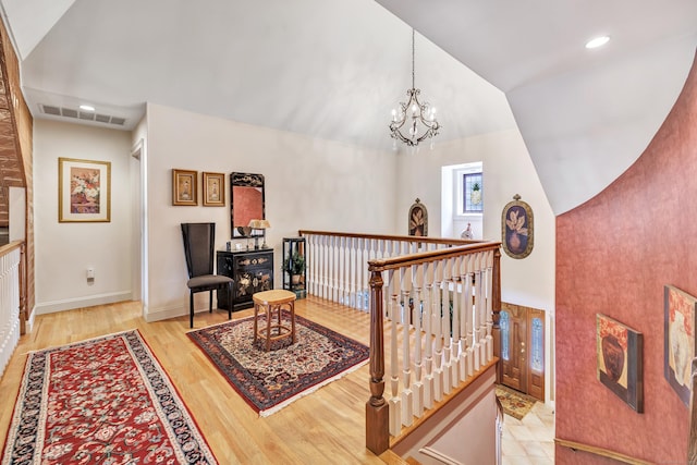 interior space with an inviting chandelier, lofted ceiling, and light hardwood / wood-style flooring