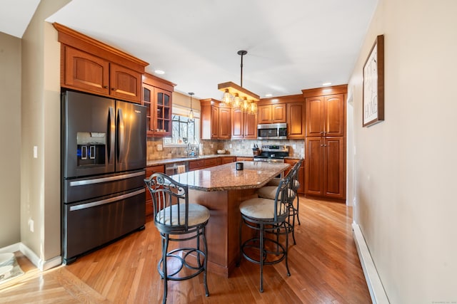 kitchen featuring pendant lighting, stone countertops, appliances with stainless steel finishes, backsplash, and a kitchen island