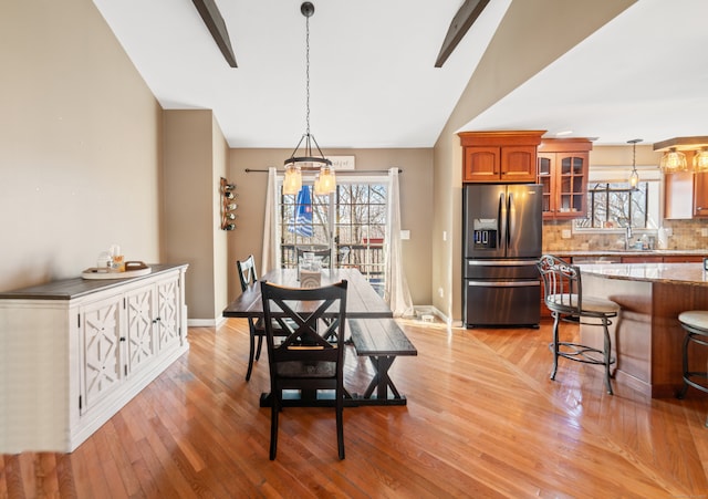 dining space with vaulted ceiling, a healthy amount of sunlight, and light hardwood / wood-style floors