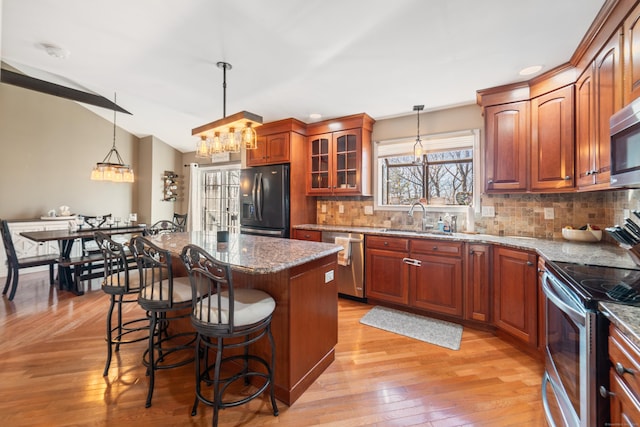 kitchen featuring pendant lighting, sink, stainless steel appliances, and a center island