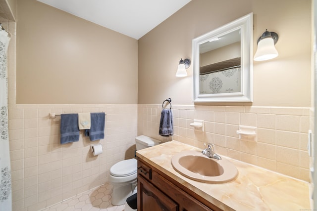 bathroom with tile patterned floors, vanity, toilet, and tile walls