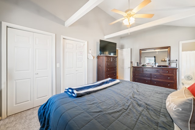 carpeted bedroom featuring connected bathroom, two closets, lofted ceiling with beams, and ceiling fan