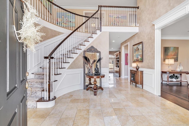 entryway featuring a decorative wall, stairway, and crown molding