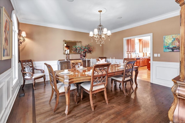 dining room featuring visible vents, a wainscoted wall, ornamental molding, dark wood finished floors, and an inviting chandelier