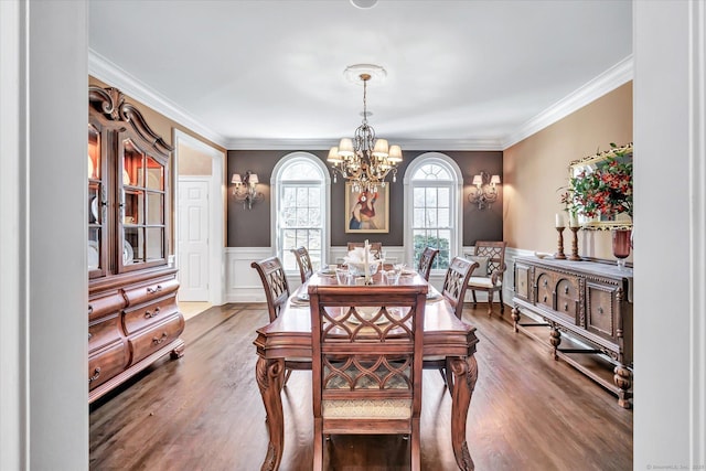 dining room with a notable chandelier, wood finished floors, wainscoting, and crown molding