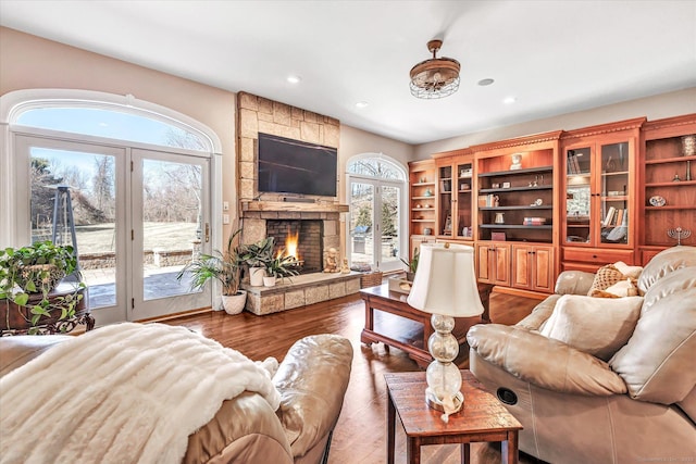 living room with recessed lighting, a large fireplace, and dark wood-type flooring