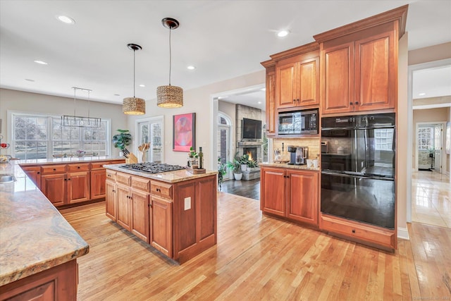 kitchen with a healthy amount of sunlight, light wood-style floors, light stone countertops, and stainless steel appliances