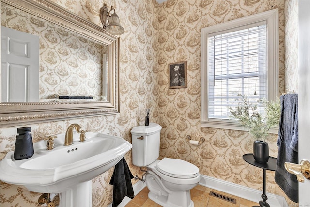 bathroom featuring visible vents, toilet, a sink, tile patterned flooring, and baseboards