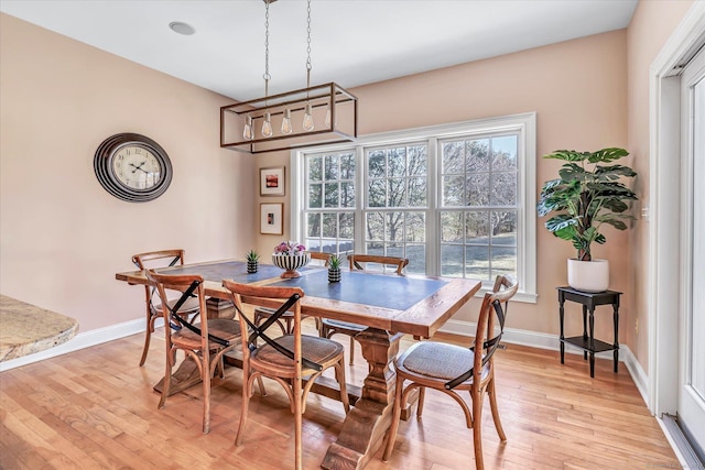 dining space with baseboards and light wood-style flooring