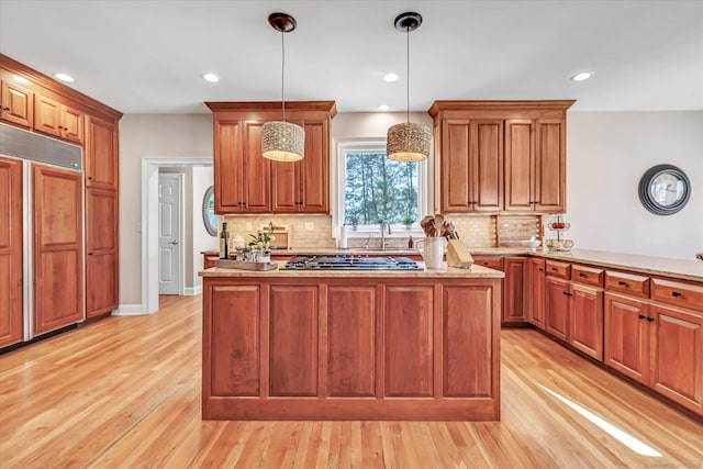 kitchen featuring stainless steel gas cooktop, pendant lighting, paneled fridge, and light wood-style floors