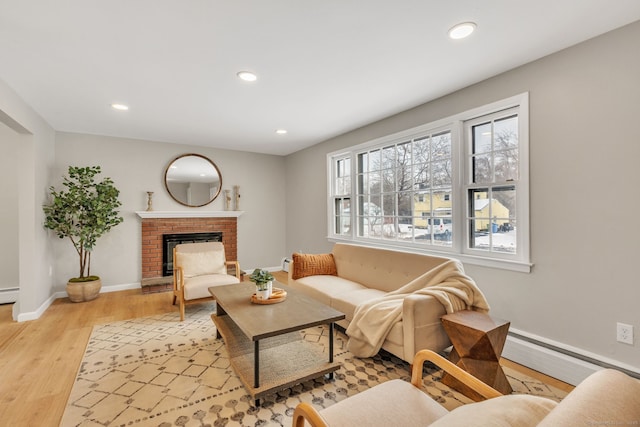 living room featuring a baseboard radiator, a fireplace, and light hardwood / wood-style floors