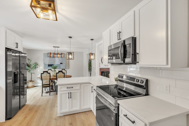 kitchen featuring pendant lighting, stainless steel appliances, white cabinets, and light wood-type flooring