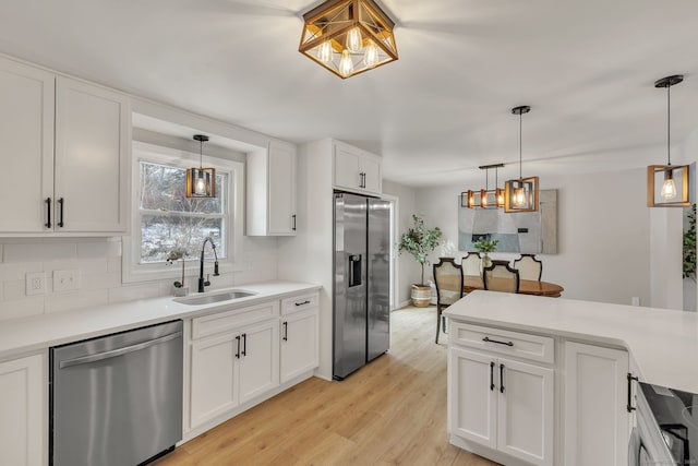 kitchen featuring sink, white cabinetry, tasteful backsplash, decorative light fixtures, and appliances with stainless steel finishes