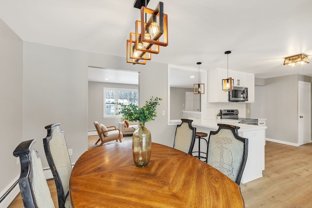 dining area featuring a baseboard radiator and light hardwood / wood-style flooring