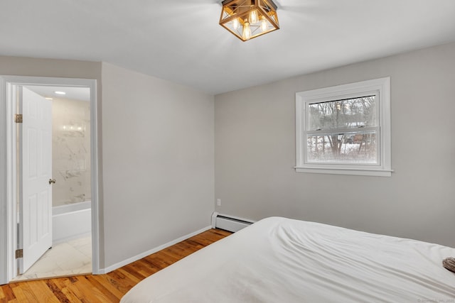 bedroom featuring ensuite bathroom, baseboard heating, and light hardwood / wood-style flooring