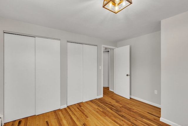 unfurnished bedroom featuring multiple closets and wood-type flooring