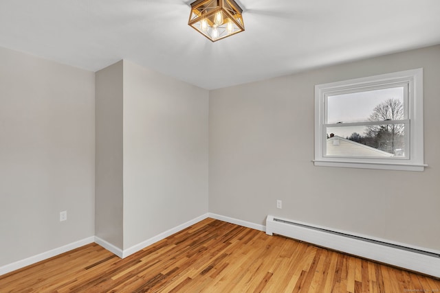 empty room featuring a baseboard heating unit and light hardwood / wood-style floors