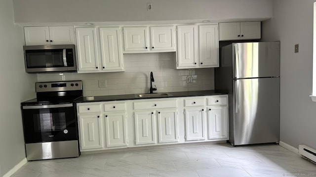 kitchen with sink, baseboard heating, appliances with stainless steel finishes, white cabinets, and decorative backsplash