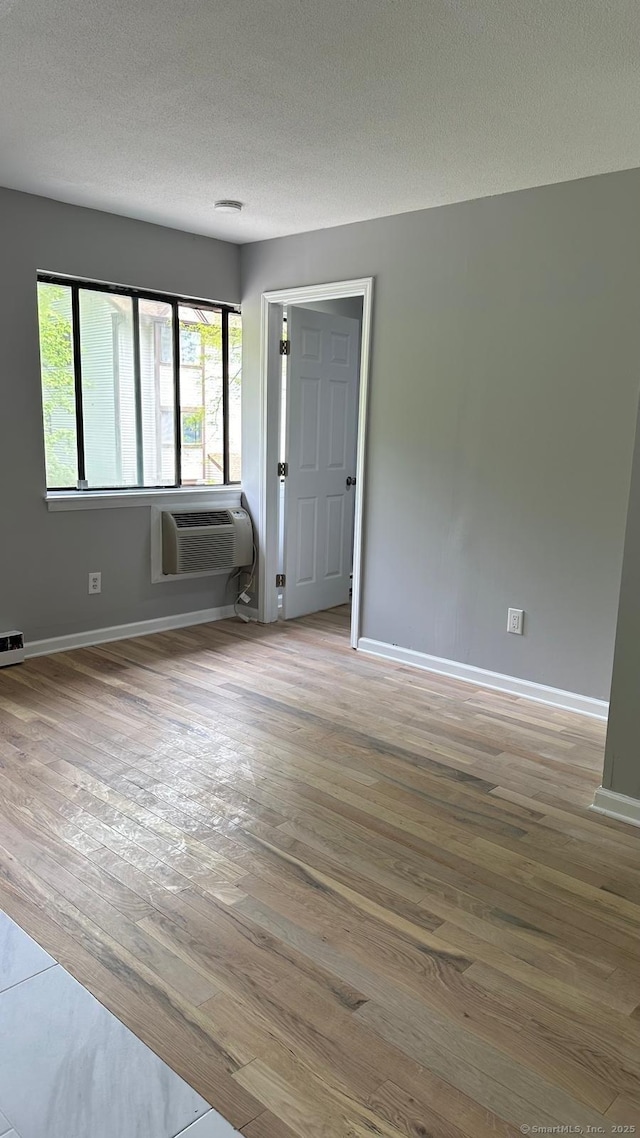 empty room featuring hardwood / wood-style floors, a textured ceiling, and an AC wall unit