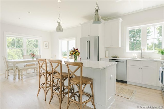 kitchen with appliances with stainless steel finishes, hanging light fixtures, sink, and a kitchen island