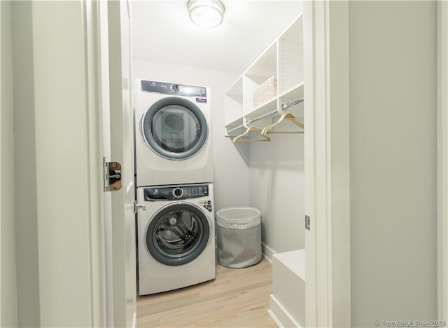 laundry room with stacked washing maching and dryer and light hardwood / wood-style floors