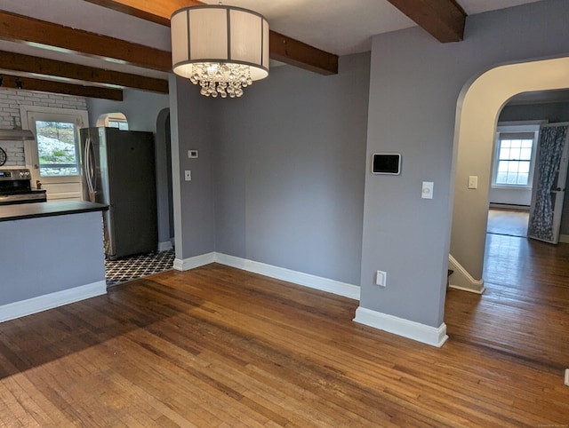 interior space featuring wood-type flooring, a notable chandelier, beam ceiling, and baseboard heating