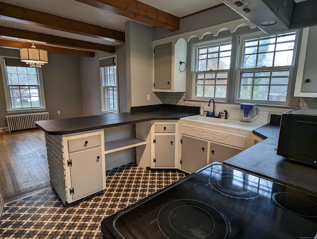 kitchen featuring radiator heating unit, white cabinets, beam ceiling, and kitchen peninsula