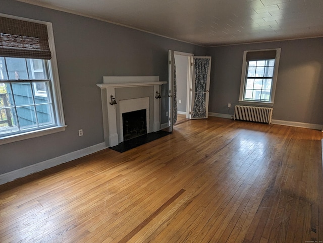 unfurnished living room featuring crown molding, radiator heating unit, and light hardwood / wood-style flooring